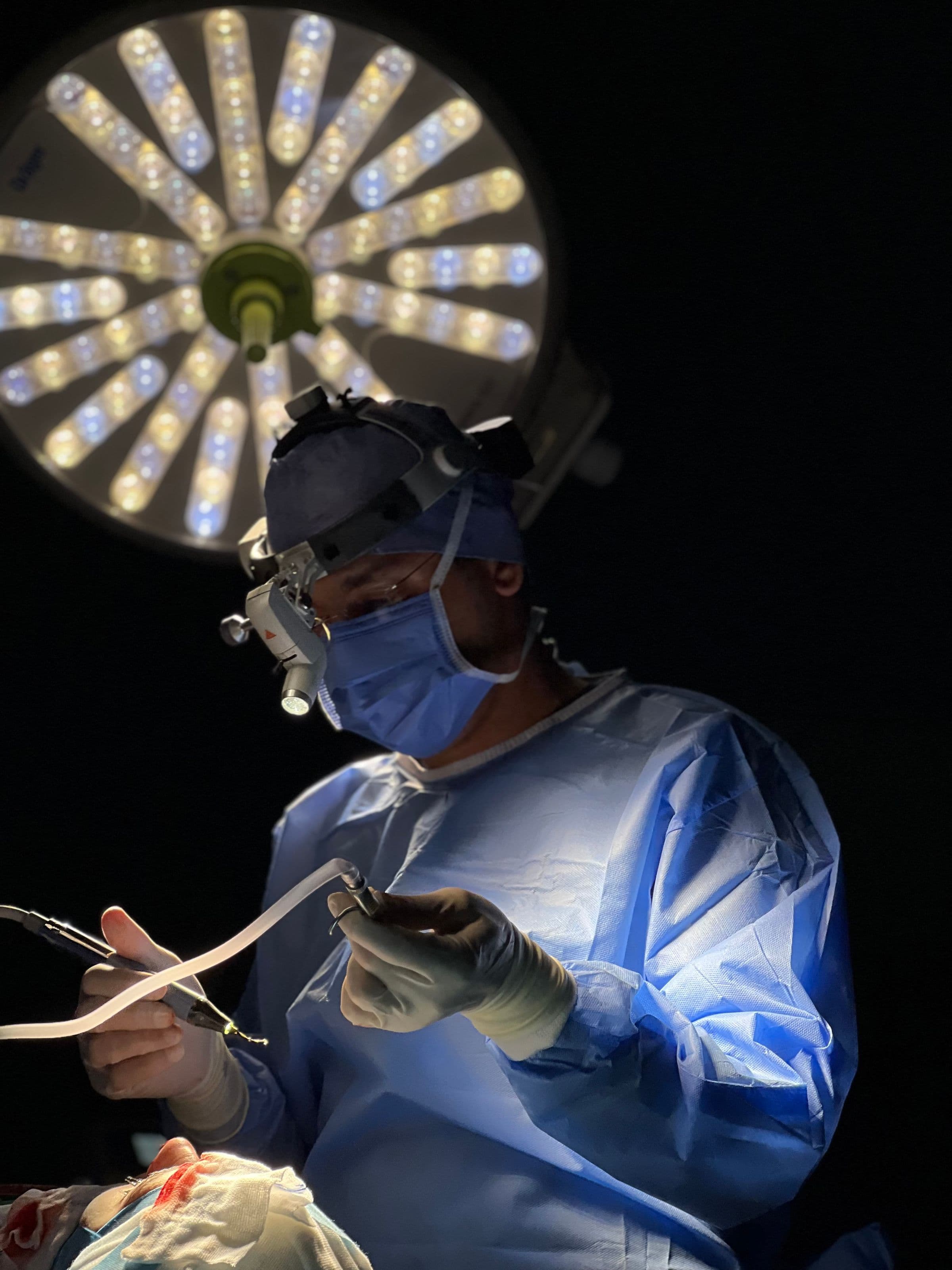 Surgeon wearing loupes under a circular operating-room light