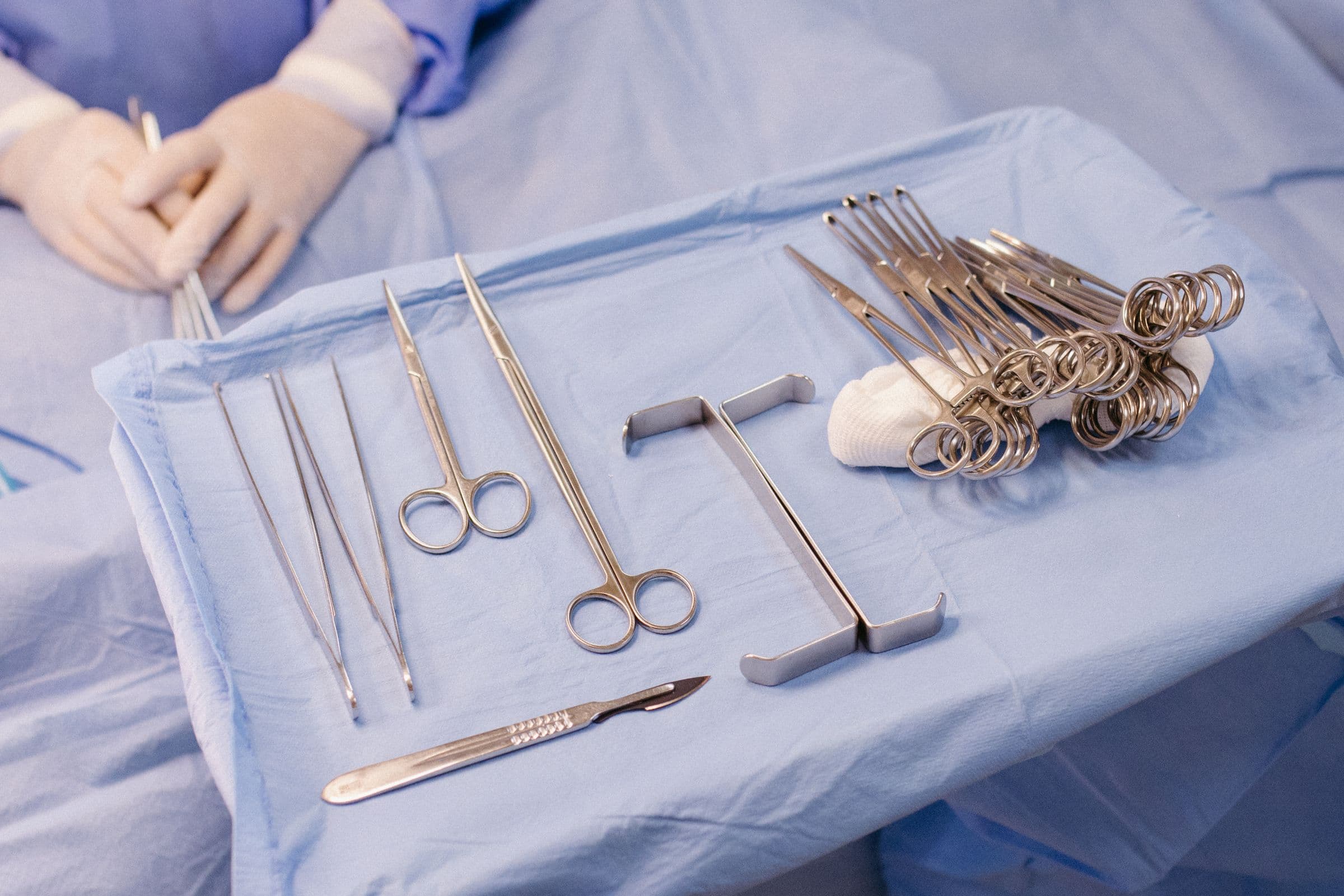Gloved hands and surgical instruments on a sterile drape